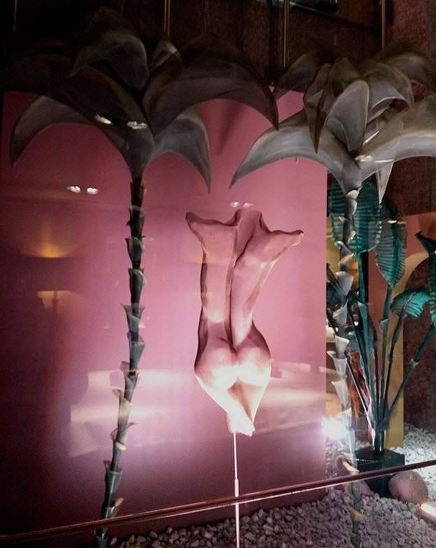 Esculturas de malla metálica de cuerpos con platanero dentro de la galería acristalada